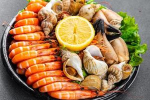 Fruit de mer assiette assorti crevettes, Crabe les griffes, palourdes, rapan, trompette mollusque repas nourriture casse-croûte sur le table copie espace nourriture Contexte rustique Haut vue photo