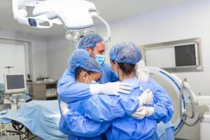 professionnels de la santé s'embrassant en soins intensifs. les médecins et les infirmières portent des combinaisons de protection après un traitement réussi. ils sont à l'hôpital pendant le covid-19. photo