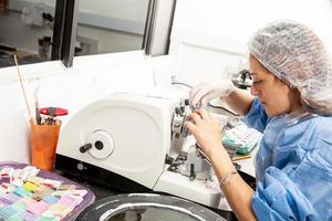 Jeune femelle scientifique travaux sur une rotatif microtome à obtenir sections de une inclus en paraffine spécimen. photo