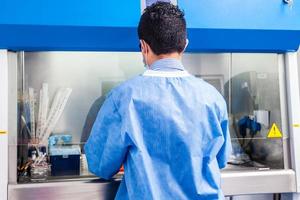 Jeune scientifique travail dans une sécurité laminaire air couler cabinet à laboratoire photo