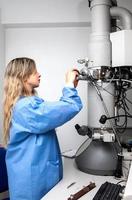 Jeune femelle scientifique chargement une spécimen en utilisant une échantillon titulaire dans une transmission électron microscope photo
