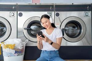 asiatique femmes sont écoute à la musique à le blanchisserie magasin. photo