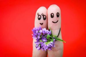 visage peint sur des doigts. homme est donnant fleurs à une femme. photo