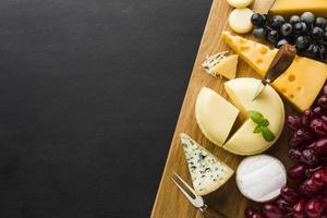 Mélange plat de fromage et de raisins gastronomiques sur une planche à découper avec espace de copie
