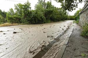 une Naturel catastrophe de inondation, boueux ruisseaux de l'eau avec des pierres et boue dans le des rues de le ville. photo