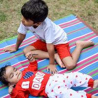 deux content garçons dans société parc, content asiatique frères qui sont souriant Heureusement ensemble. frères jouer en plein air dans été, meilleur amis. bambin bébé garçon en jouant avec le sien content frère dans le jardin photo