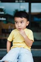 portrait de un asiatique garçon portant une Jaune T-shirt. flou Contexte. photo