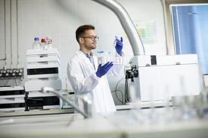 Jeune chercheur travaillant avec des échantillons chimiques en laboratoire avec système hplc et équipement de chromatographie photo