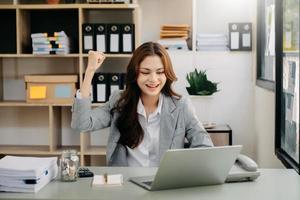 les femmes d'affaires asiatiques sont ravies et satisfaites du travail qu'elles font sur leur tablette, leur ordinateur portable et en prenant des notes au bureau. photo