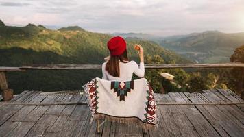 image de vue arrière d'une femme voyageuse assise et regardant une belle vue sur la montagne, le champ de fleurs et la nature photo