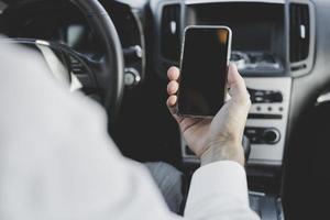 Close-up man's hand holding mobile phone avec écran vide dans la voiture photo
