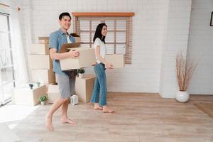 content Jeune couple porter papier carton des boites et en marchant de le de face porte dans le maison dans une Nouveau maison à en mouvement journée. concept de déménagement, de location, et propriétaire en mouvement à maison. photo