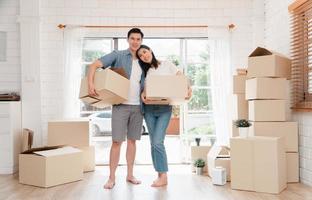 content Jeune couple porter papier carton des boites et en marchant de le de face porte dans le maison dans une Nouveau maison à en mouvement journée. concept de déménagement, de location, et propriétaire en mouvement à maison. photo