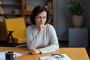 triste fatigué mauvais malade solitaire déçu plus âgée Sénior femme séance à Accueil seule. malheureux mature grand-mère expérience douleur relatif décès mal nouvelles. stressé aîné Dame Souffrance de solitude. photo