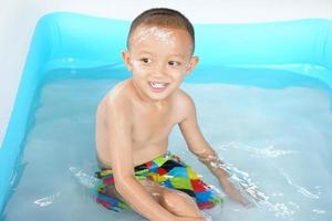 chaud temps. garçon en jouant avec l'eau Heureusement dans le baignoire. photo