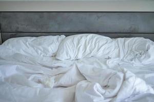 désordonné blanc lit dans de bonne heure Matin , désordonné lit après veille en haut photo