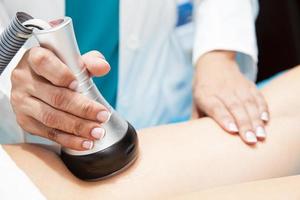 médecin performant un ultracavitation traitement sur une Jeune femelle patient jambe photo