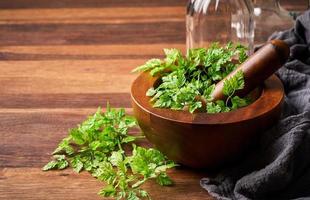 concept de herbe vert cerfeuil dans une en bois mortier avec verre bouteilles et en tissu sur bois table Contexte photo