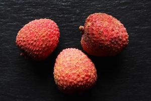 Trois litchis isolés sur fond d'ardoise pour des illustrations alimentaires photo