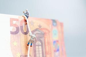 personnes miniatures, grimpeur grimpe sur un billet en euros, concept d'entreprise. photo