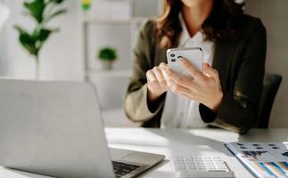 sur de soi femme d'affaires travail sur ordinateur portable, tablette et tablette à sa lieu de travail à bureau. photo