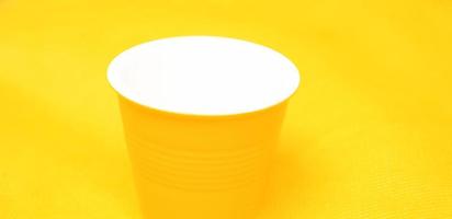 gobelet en plastique jaune sur une surface jaune photo