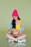 élégant Jeune femme enceinte mère dans élégant vêtements sur un olive Contexte photo