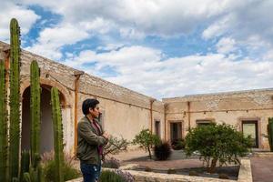 homme visite le vieux rustique modèle école avec cactus dans minéral de pozos guanajuato Mexique photo