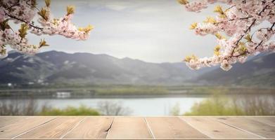 vide en bois table avec printemps Cerise fleur décoration. flou bokeh Montagne et Lac vue Contexte. copie espace. pour produit afficher. modèles, médias, impression, etc., produire ai photo