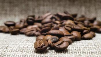 Tas de grains de café torréfiés sur un tapis macro, fond beige close up