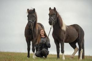 Jeune femme suédoise dans un champ avec ses deux chevaux islandais photo