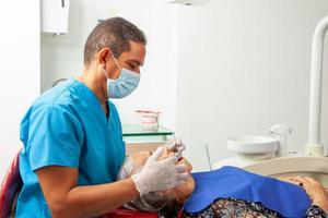 Sénior femme patient à une Masculin milieu -vieilli dentiste Bureau photo