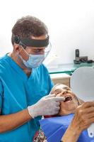 Masculin milieu -vieilli dentiste à le sien Bureau avec une Sénior femme patient photo