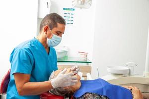 Masculin milieu -vieilli dentiste à le sien Bureau avec une Sénior femme patient photo