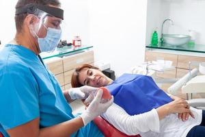 Masculin âge moyen orthodontique spécialiste dentiste à le sien Bureau en utilisant une dentaire modèle à Explique le traitement à le sien patient photo