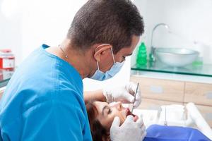 Masculin âge moyen dentiste à le sien Bureau avec une femelle patient photo