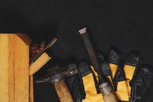 ensemble d'outils pour charpentiers, marteau, ciseau et avion avec fond en bois foncé gants. photo