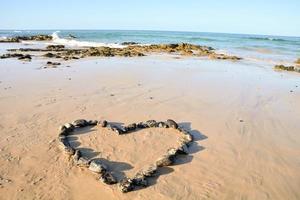 cœur forme sur sec le sable près le l'eau photo