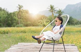 mignonne fille asseoir et se détendre sur chaise et Jaune fleur arrière-plan,. photo