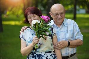 content personnes âgées couple avec fleurs. Beau homme et femme Sénior citoyens. mari et épouse de vieux âge dans le parc. photo