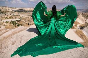une fille dans une en volant robe avec une longue train sur le Contexte de des ballons dans cappadoce. photo