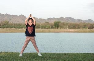 mignonne fille exercice sur vert herbe sur soir. photo