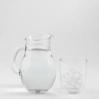 Pichet en verre de verre d'eau rempli de glace sur fond blanc