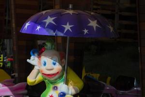 jouet brillant pitre en dessous de une bleu parapluie. photo