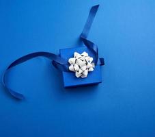 bleu carré boîte avec une cadeau avec une arc sur une bleu classique arrière-plan, Haut vue photo