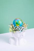 enregistrer le planète, Terre journée concept. Créatif plâtre vase forme de tête avec fleurs et monde globe. photo