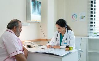 une femelle médecin examine le maladie et donne Conseil sur prise médicament. pour personnes âgées les patients recevoir traitement photo