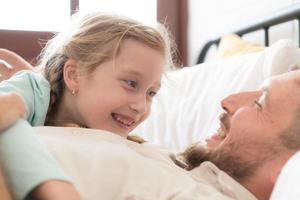 une père jouit parlant avec le sien fille dans le sien chambre à coucher. avant en disant Au revoir et Envoi en cours sa fille à lit photo