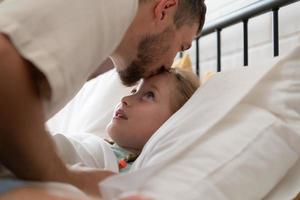 avant sortant à nuit, une père exprime le sien affection par embrasser le sien fille sur le front. à avoir une bien nuits du repos photo