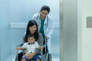 une pédiatre aide à pousser fauteuil roulant les mères et les enfants à examiner le corps dans une spécial pièce de le hôpital photo